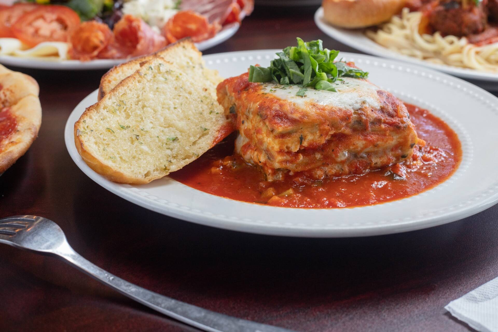 Piece of the delicious Italian Lasagna on a white plate with a fork